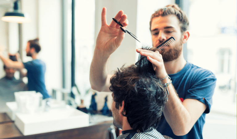 Hairdresser in a blue t-shirt cutting another person's hair