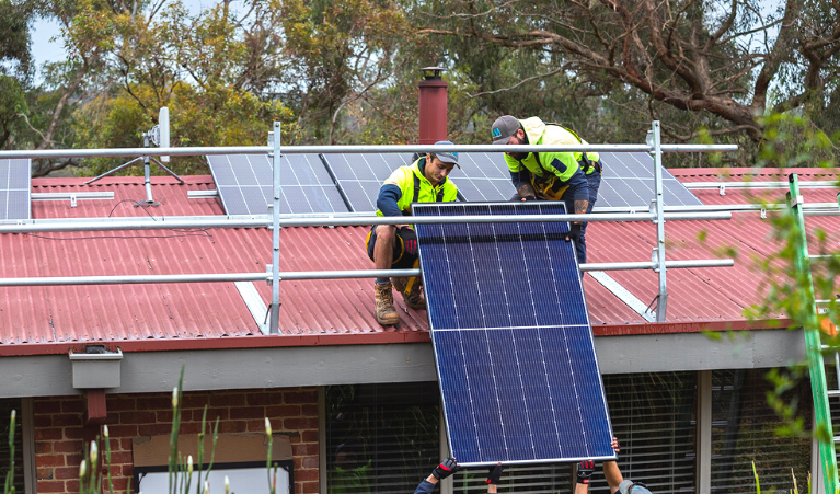 Solar installers installing a solar panel to the roof