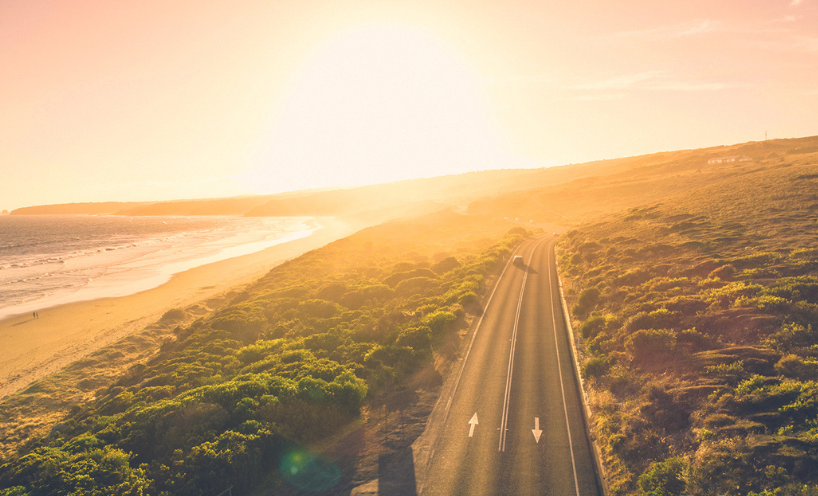 sunset on an ocean road with green trees