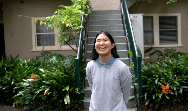 Tia smiling in front of her townhouse with a solar panel